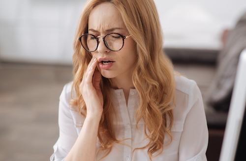 woman holding her jaw from infected tooth pain
