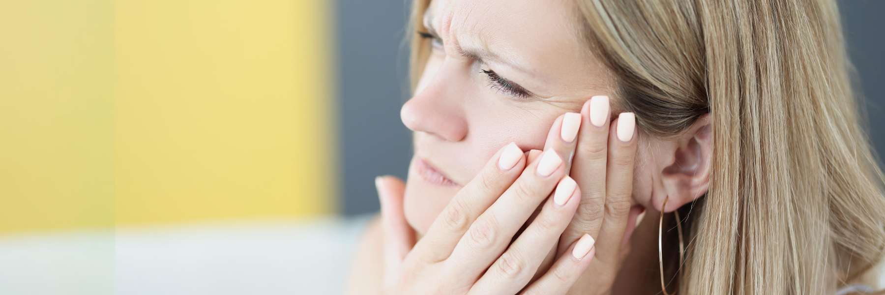 A woman with her hand on her face, reflecting concern about dental emergencies in Duncan.