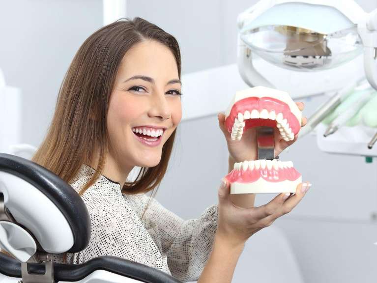 duncan woman holding tooth mold while sitting in dental chair