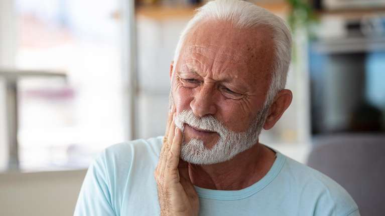 man in pain holding jaw during a dental emergency 