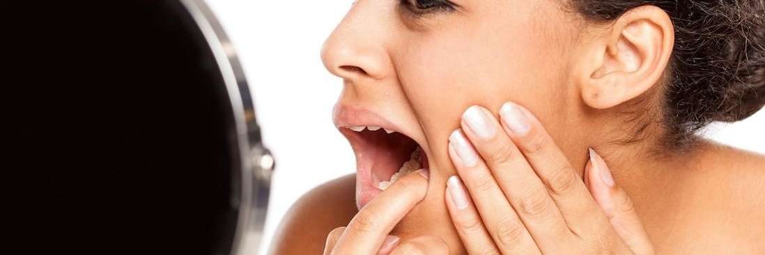 duncan woman checking teeth in mirror during a dental emergency